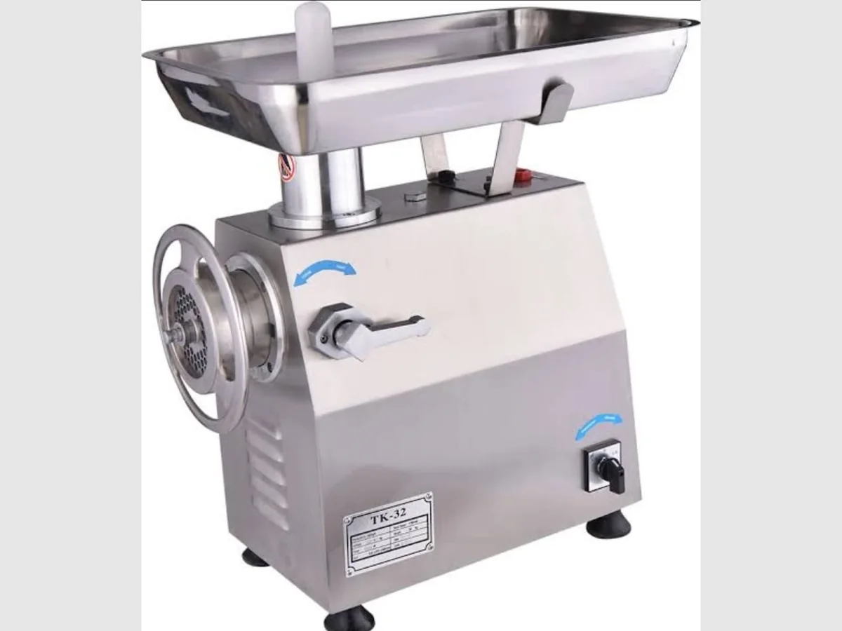 Mincer 32 Stainless steel electric meat mincer with feed tray, hand wheel and perforated mincing plate, labelled TK-32