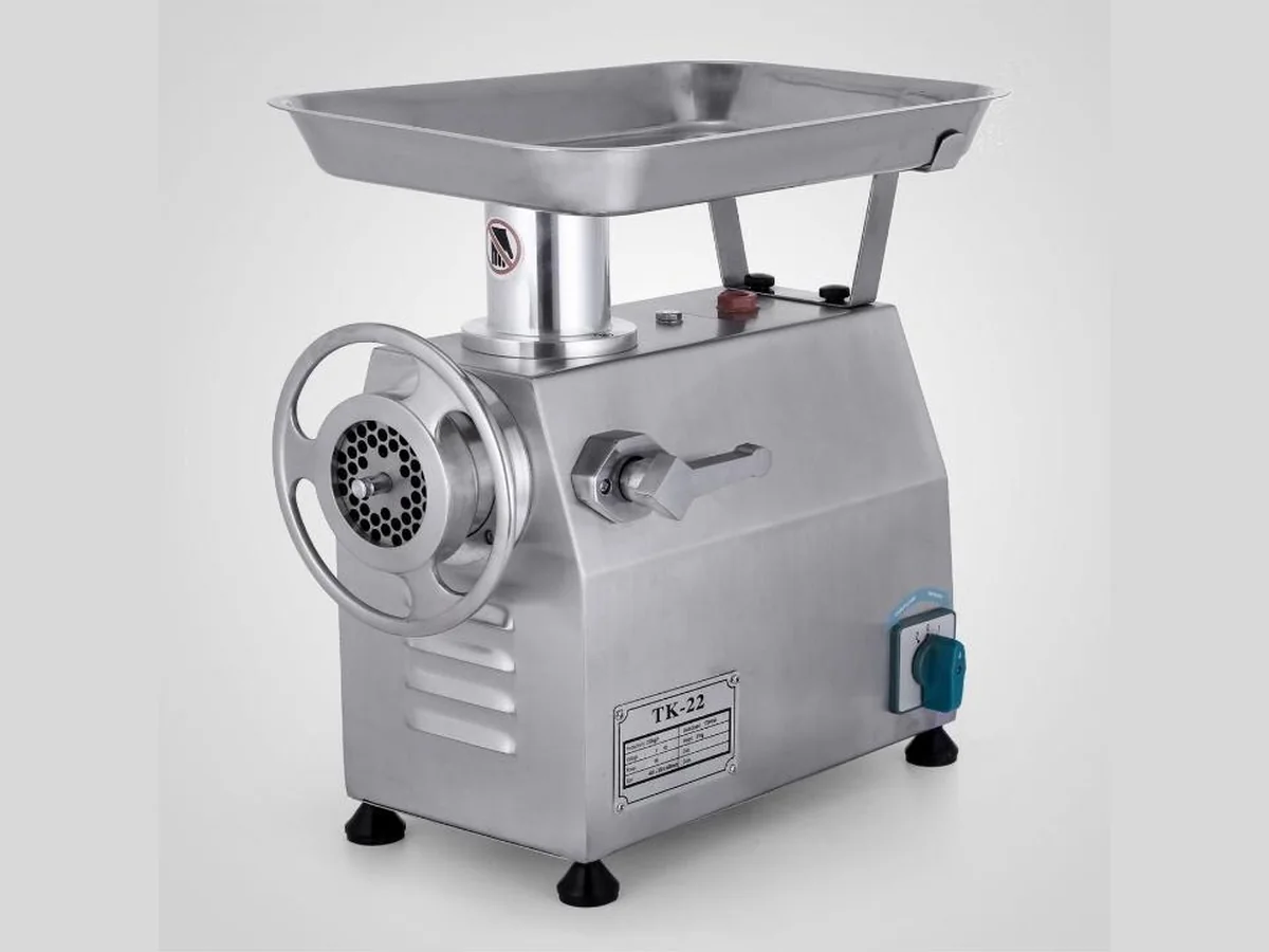 Mincer 22 Stainless steel electric meat mincer with feed tray, hand wheel and perforated mincing plate, labelled TK-22
